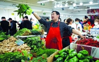 Китаец-продавец овощей выкрикивает цены на рынке Пекина